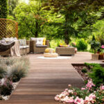 Beautiful wooden terrace with garden furniture surrounded by greenery on a warm, summer day